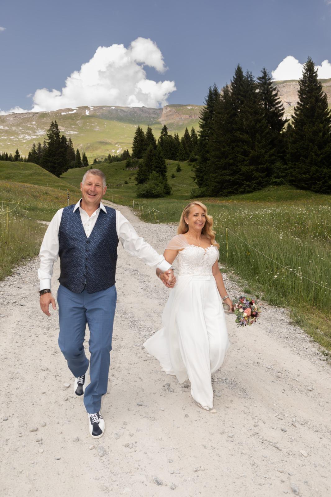 Foto eines Brautpaares in den Bergen im Sommer 2026, die Braut trägt einen modernen Look von Zauberbraut.